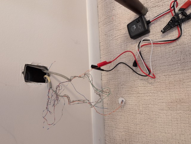 Cable toner attached to twisted pair wiring coming out of the wall