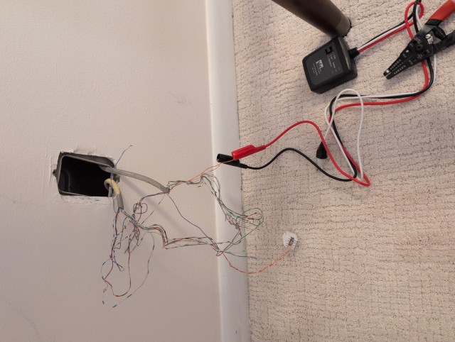 Cable toner attached to twisted pair wiring coming out of the wall