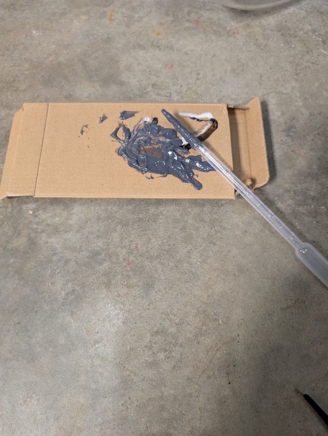 gray mixed jb-weld on a scrap cardboard box