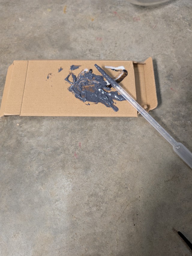 gray mixed jb-weld on a scrap cardboard box